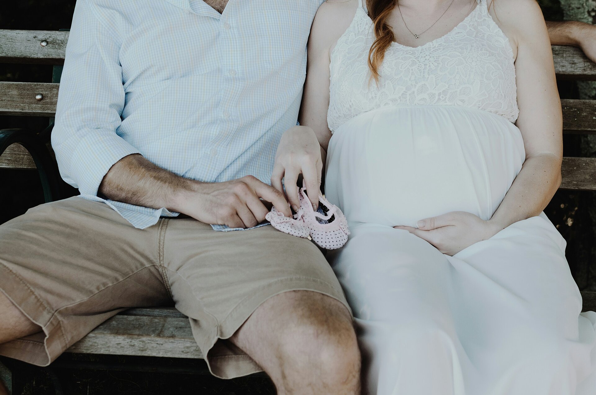 Foto eines Paares, die gemeinsam Babyschüchen tragen. Die Frau auf dem Bild ist schwanger.